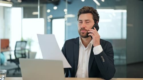 Man In Suit Talking On Phone Holding Paper