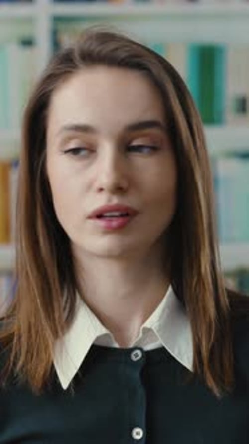 Une jeune femme est dans une bibliothèque et participe à une conversation intellectuelle réfléchie