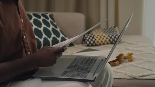 Man Reviews Documents and Uses Laptop at Home