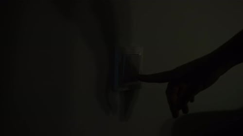 Mão aproximada da mulher acendendo e desligando a luz na sala pressionando o botão na parede branca.