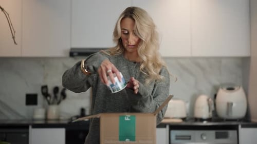 Woman Unboxing Package in Modern Home Kitchen
