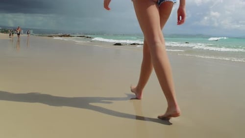 Young Woman Walking Along Beach Barefoot in Short Shorts with Ocean And