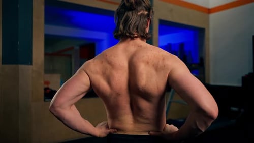 In the Gym Young Handsome Trainer Warms Up His Back Bending and Unbending Demonstrating His Back