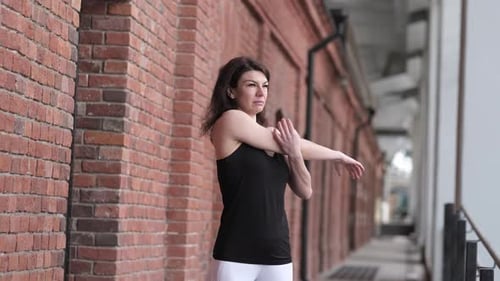 Woman Stretching Arms Near Brick Wall