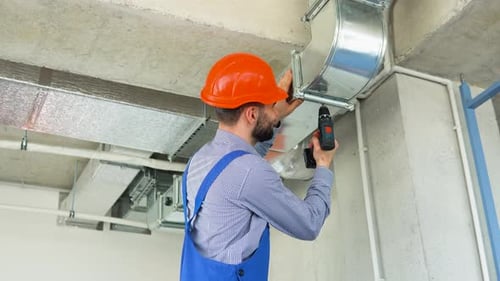 Man Securing Air Conditioning Duct with Drill