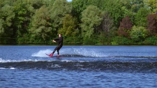 Wakeboarder jumps and performs tricks on river during summer holiday
