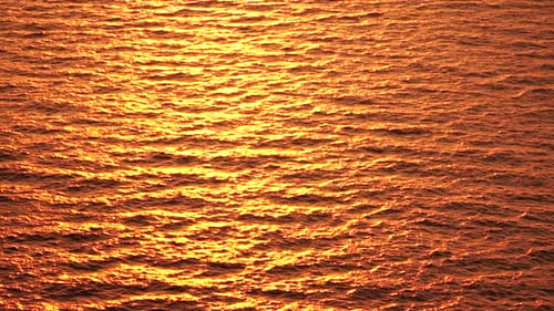 Luftaufnahme der Meereswasseroberfläche auf goldenem Meerwasser bei Sonnenuntergang, Sonnenblendung, abstrakter nautischer Sommerozean