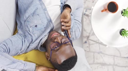 Vertical Video of Top view of young African man with glasses talking on the phone.