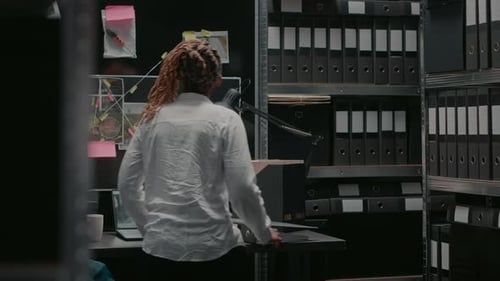 Adult Placing Binder on Desk in Dark Office