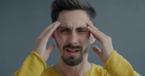 Man Rubbing Temples with Headache in Close Up