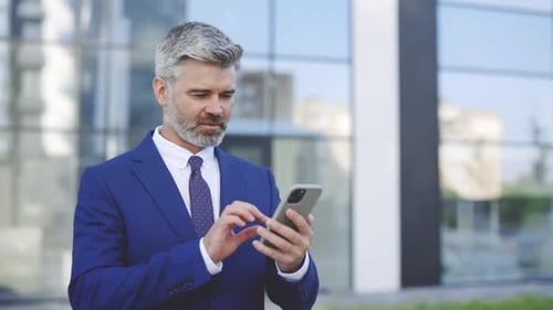 Successful Man Celebrating with Smartphone Outside Modern Building