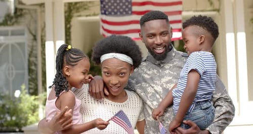 Happy Family Poses with American Flags Outside Home