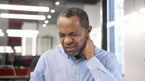 Man in Pain Holds Neck in Office Setting