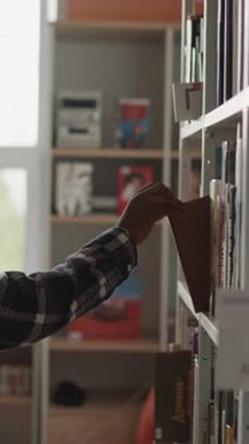 Man Picks Up Book From Shelf in Library