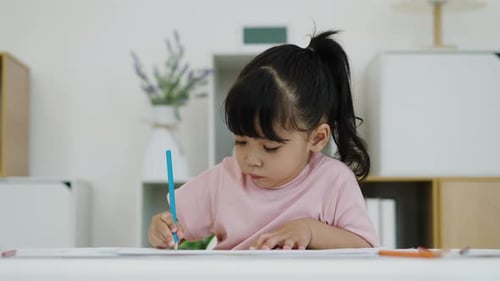 petite fille s'entraînant à dessiner avec un crayon de couleur sur un bureau à la maison