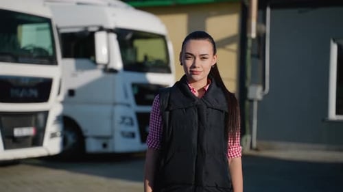 Female Logistics Worker Standing Near Trucks Outdoors