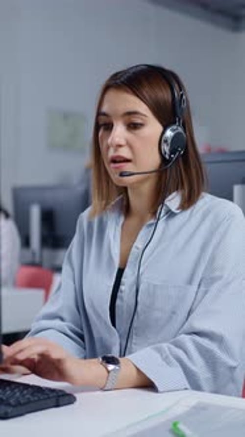 Focused Female Call Center Agent Wearing Headset and Working at Computer in Modern Customer Support