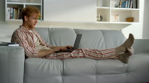 Young Man Using Laptop on Sofa Indoors