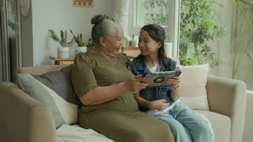 Grandmother and Granddaughter Using Tablet on Couch
