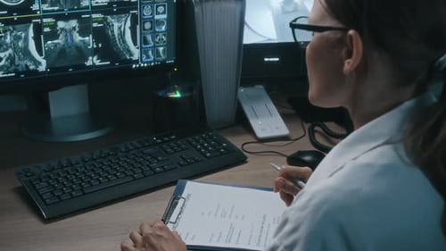 Woman Doctor Working on Medical Chart, Examining Scans