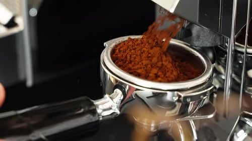 Using a grinder machine to grind fresh coffee beans to make hot beverages at coffee shop