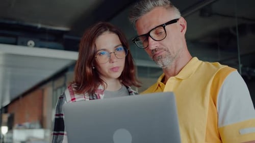 Une stagiaire se tient à côté d'un programmeur et demande des conseils