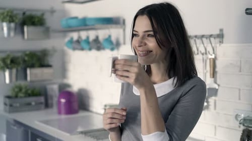 Woman Enjoying a Cup of Coffee in Kitchen