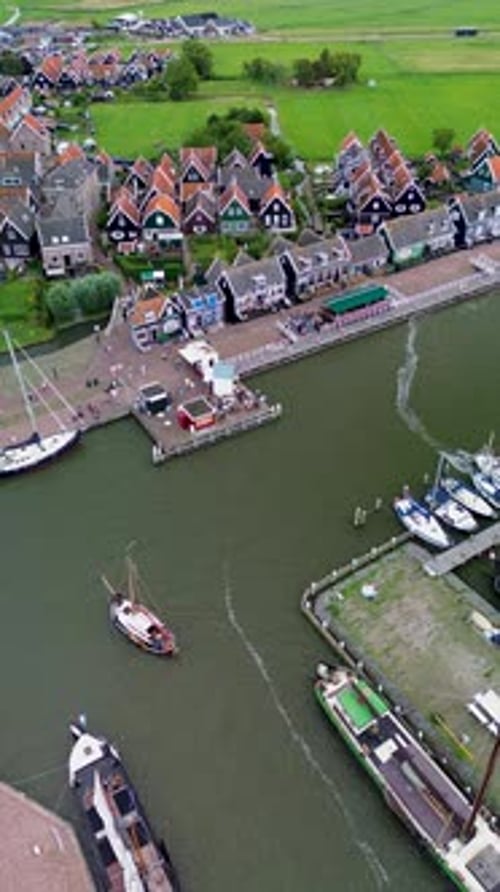 Aerial view of a Dutch harbor with sailboats, traditional black wooden houses with red roofs