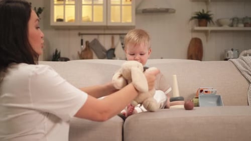Mother Plays with Baby on Couch with Toys