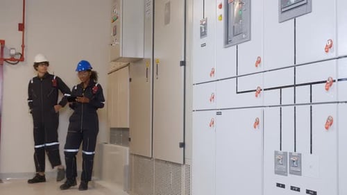 Engineers Inspecting Electrical Panels in Bright Industrial Setting