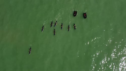 Aerial drone view rotating shot of a rowing team of sport kayak practicing with black boats in the o