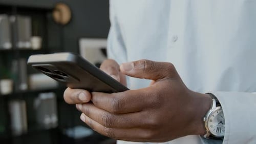 Hands of Black Male Executive Typing on Smartphone in Office
