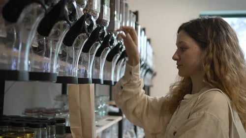 Mujer joven vierte garbanzos en una bolsa de papel para manualidades en una tienda sin empacar