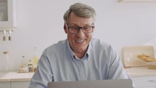 Senior Man Using Laptop in Bright Kitchen