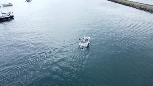 Following speed boat aerial view navigating quiet river Conwy harbour marina seaside town slow follo
