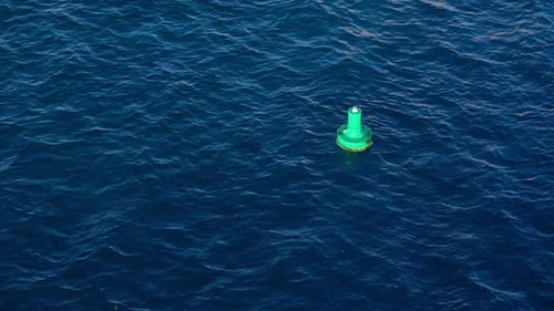 Green buoy rocks in deep blue Caribbean ocean water