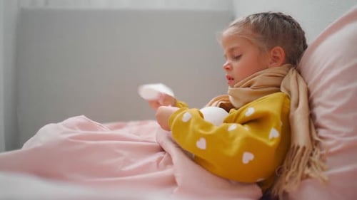 Child With Cold Using Tissues in Bed