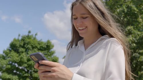 Smiling Woman Using Mobile Phone Outdoors