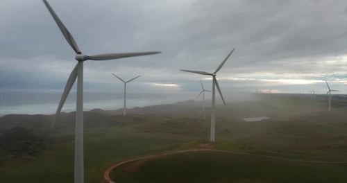 Aerial shot of wind mills rotating by the force of the wind and generating renewable energy in a g