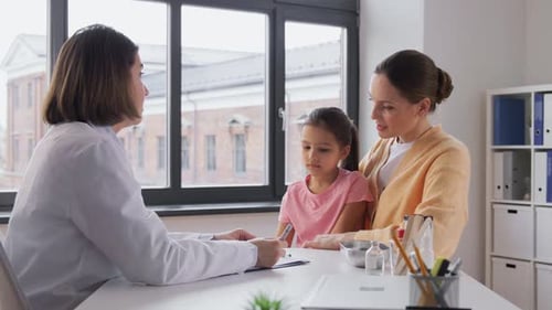 Doctor consults with child and her mother at desk