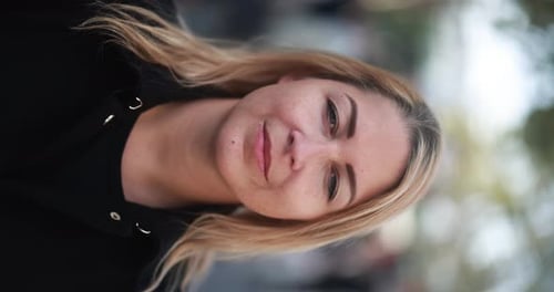 Young blonde woman looking on camera in the city - Vertical video