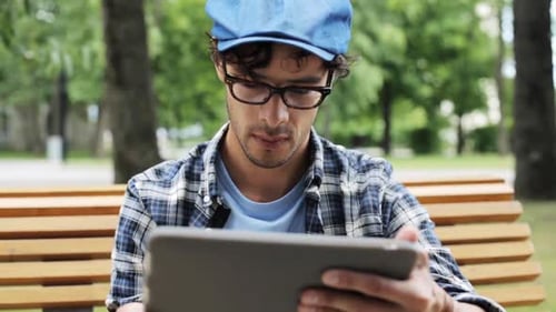 Creative hispanic man browsing on tablet computer by fixed gear bike in city street