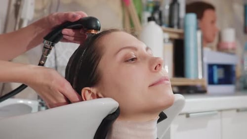 Wash Shower Basin Closeup Woman Reclining with Eyes Closed While Stylist Rinses Hair Gentle Spray
