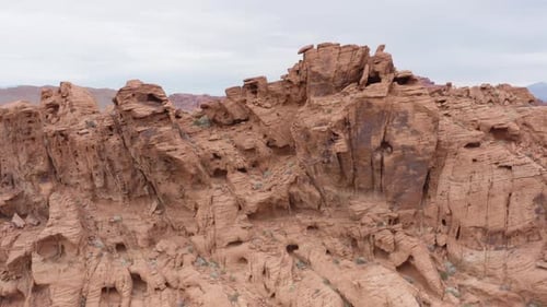 Cinematic aerial pull back shot of arid red sandstone rock formation resembling landscape on Mars