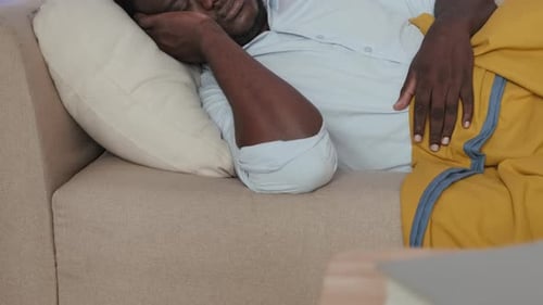 Homme noir dormant sur un canapé dans le salon la nuit