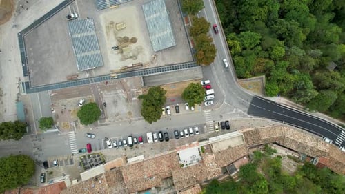 Top-down aerial view showcasing a mix of urban and natural elements, with a parking lot, curved road