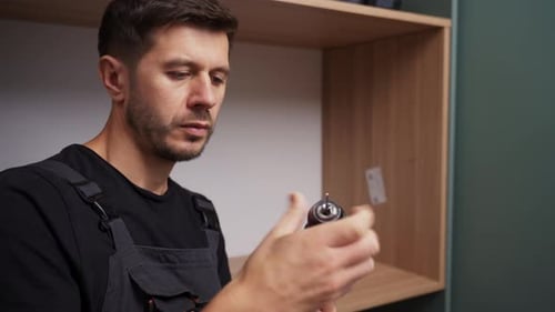 Homme en tenue de travail préparant une perceuse pour l'assemblage de meubles