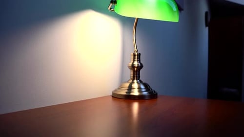 Green Reading Lamp on an empty, brown desk. The lamp is on.