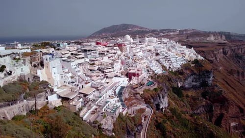 Aerial view overlooking the architecture of a town on the Santorini island, on a sunny evening, in G