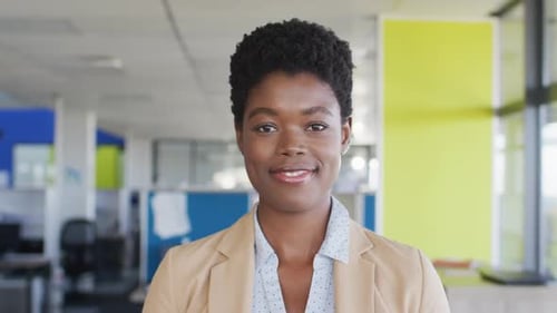 Portrait of african american businesswoman looking at camera and smiling at office, slow motion